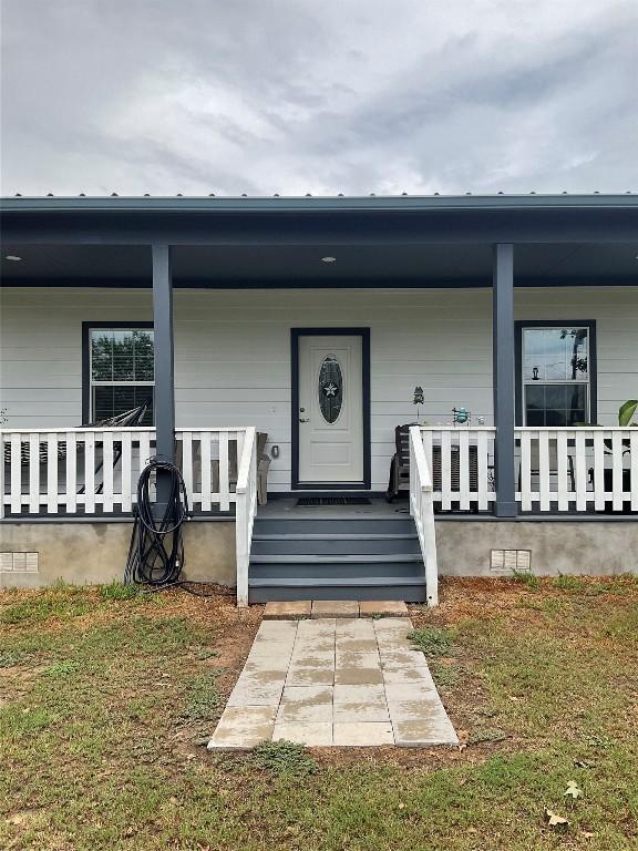 doorway to property with a porch and a yard