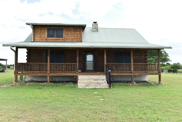 back of property featuring metal roof, covered porch, a yard, log exterior, and a chimney