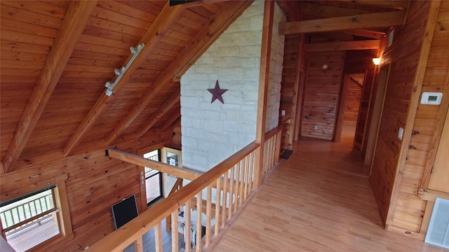 hall with light wood-style floors, wooden ceiling, vaulted ceiling with beams, and wooden walls