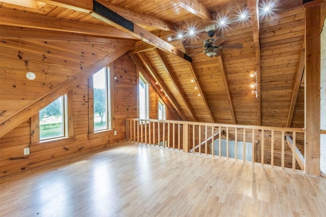 bonus room featuring vaulted ceiling with beams, a ceiling fan, wood walls, wood finished floors, and wooden ceiling