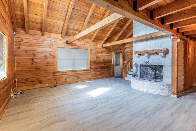 unfurnished living room featuring wooden ceiling, hardwood / wood-style flooring, wooden walls, and a stone fireplace