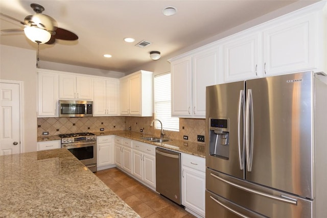 kitchen with sink, backsplash, stainless steel appliances, light stone countertops, and white cabinets