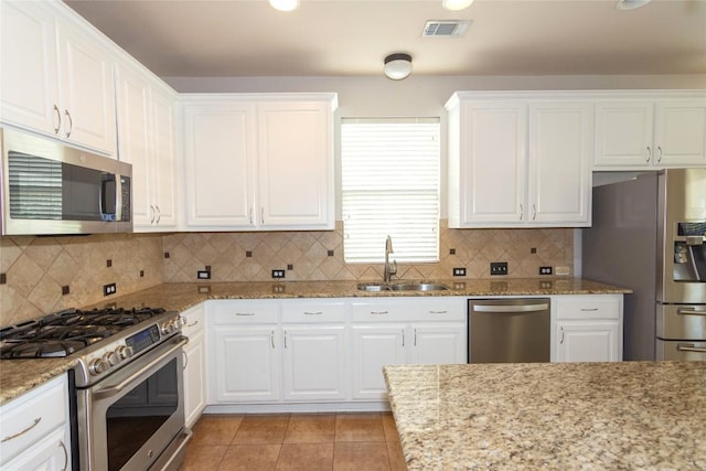 kitchen featuring light tile patterned flooring, sink, white cabinetry, stainless steel appliances, and light stone countertops