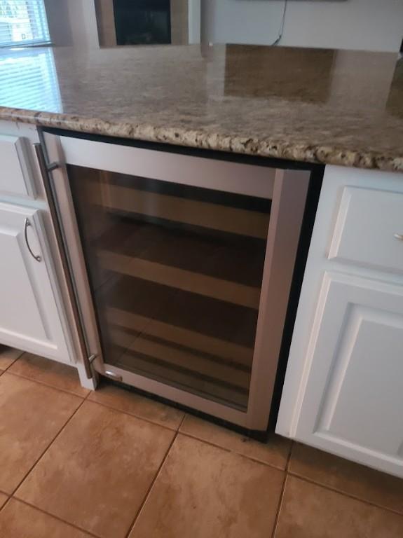 room details featuring white cabinetry, dark stone counters, and beverage cooler