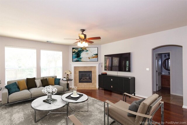 living room with dark wood-type flooring, ceiling fan, and a fireplace