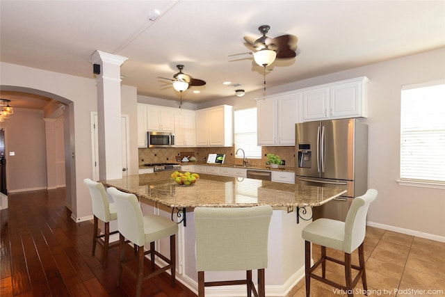 kitchen featuring white cabinetry, light stone counters, stainless steel appliances, and a kitchen island