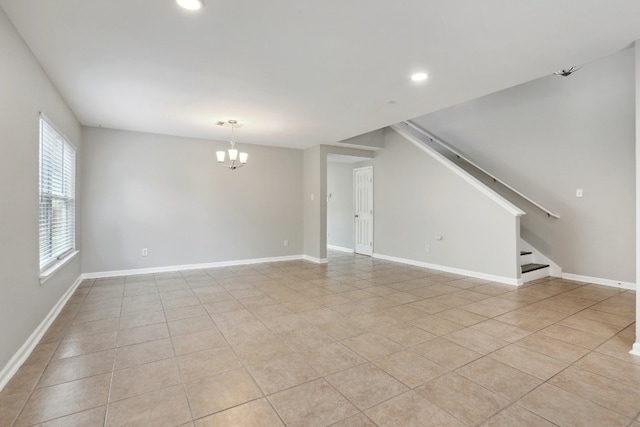 tiled empty room featuring an inviting chandelier