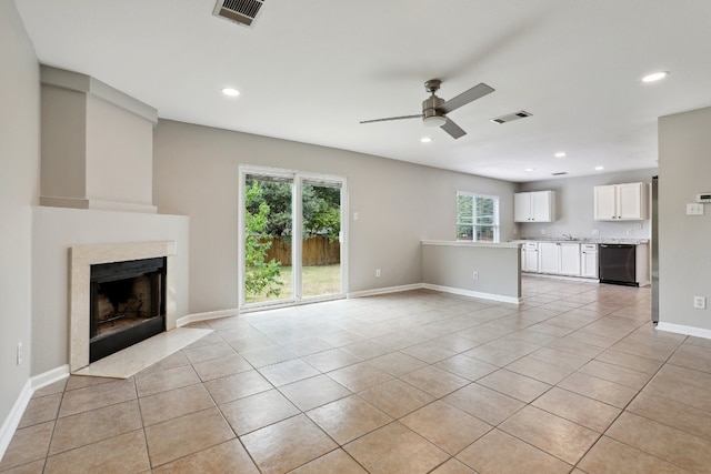 unfurnished living room with a premium fireplace, ceiling fan, and light tile patterned flooring