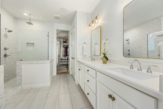 bathroom with a tile shower, vanity, and tile patterned floors