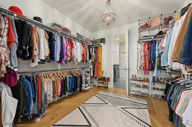 walk in closet with an inviting chandelier and light hardwood / wood-style flooring