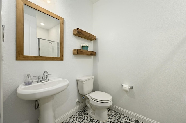 bathroom with a shower with shower door, tile patterned floors, and toilet