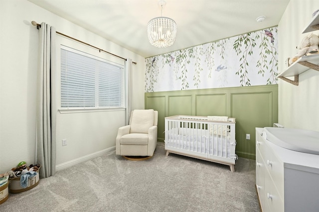 carpeted bedroom with a nursery area and a chandelier