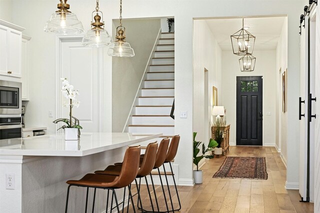 interior space with decorative light fixtures, a barn door, white cabinets, and appliances with stainless steel finishes