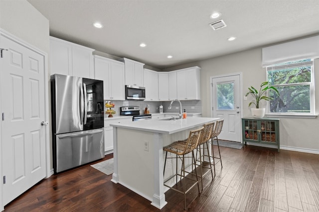 kitchen with a center island with sink, white cabinetry, dark hardwood / wood-style floors, sink, and stainless steel appliances