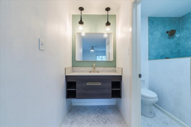 full bath with toilet, vanity, baseboards, a tile shower, and tile patterned floors