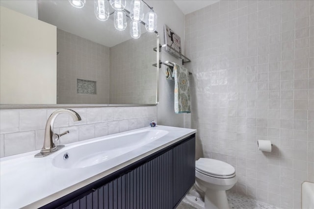 bathroom with vanity, toilet, and tile walls