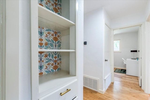 hallway featuring light wood-type flooring, visible vents, and baseboards