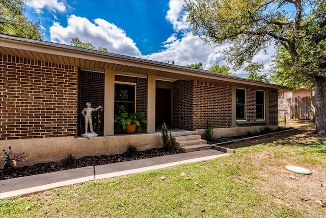 view of front of house with a front yard, fence, a porch, and brick siding