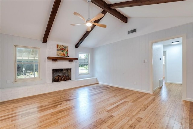 unfurnished living room featuring lofted ceiling with beams, wood finished floors, visible vents, a ceiling fan, and a brick fireplace