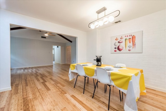 dining area with ceiling fan, light wood-type flooring, and brick wall