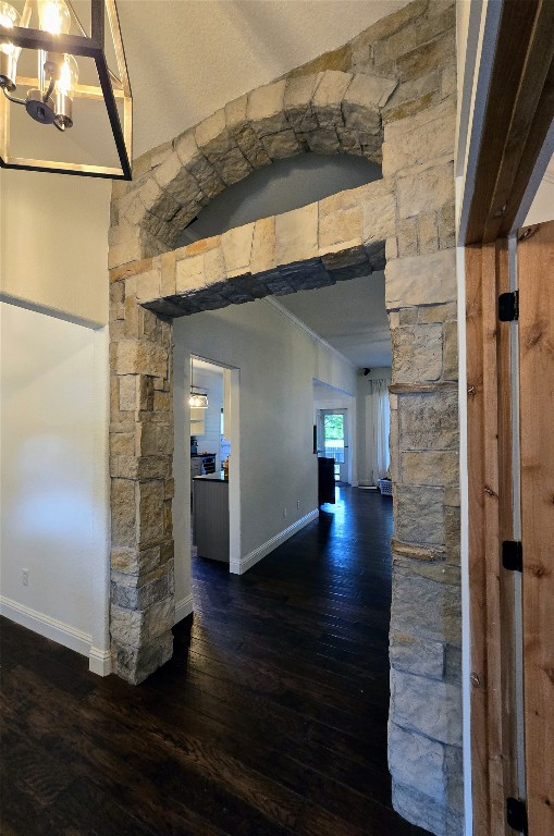 corridor featuring dark wood-type flooring and a notable chandelier