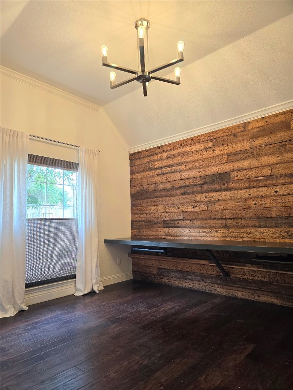 interior space featuring ornamental molding, dark wood-type flooring, vaulted ceiling, and a notable chandelier