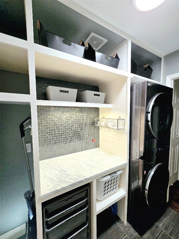 interior space with dark tile patterned floors, wine cooler, and stacked washer / drying machine