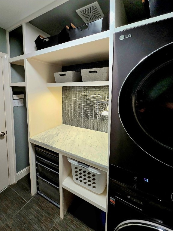 clothes washing area with stacked washer and dryer and dark hardwood / wood-style flooring