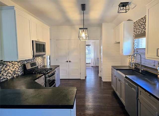 kitchen featuring dark hardwood / wood-style floors, hanging light fixtures, stainless steel appliances, sink, and white cabinetry