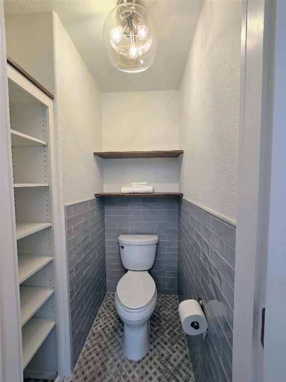 bathroom with tile patterned flooring, tile walls, and toilet