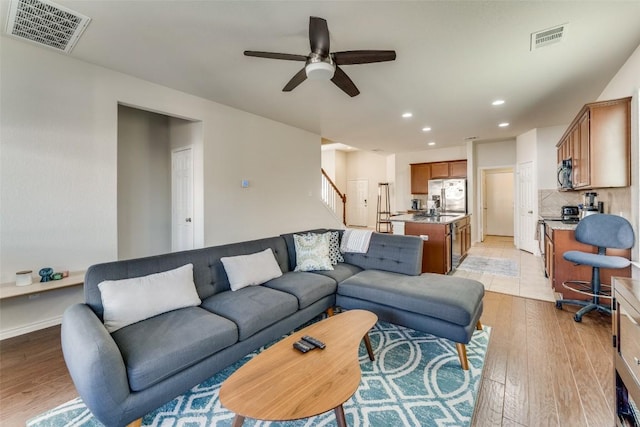 living room with ceiling fan and light hardwood / wood-style flooring