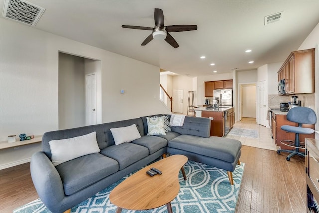 living area with light wood-type flooring, visible vents, ceiling fan, and recessed lighting