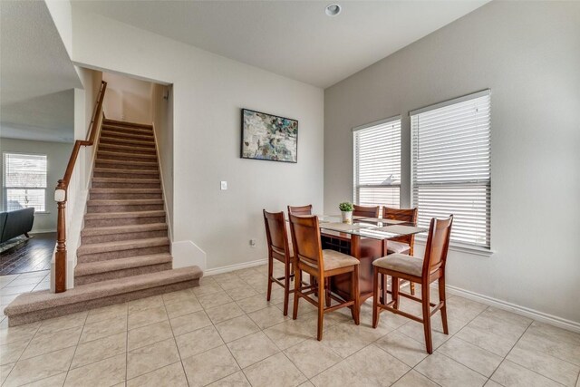 dining room with light tile patterned flooring, baseboards, and stairs