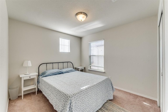 bedroom with baseboards and light carpet