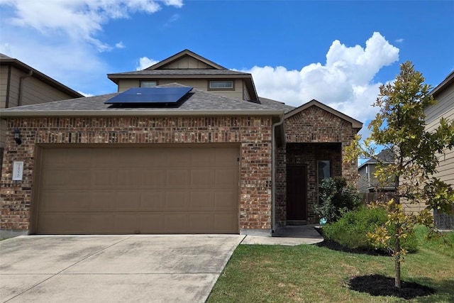 view of front of property with driveway, roof mounted solar panels, brick siding, and a garage