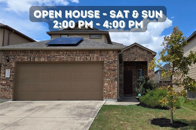 view of front of property featuring brick siding, solar panels, driveway, and an attached garage