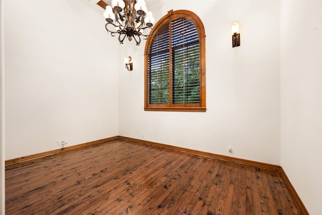 spare room with wood-type flooring and a chandelier