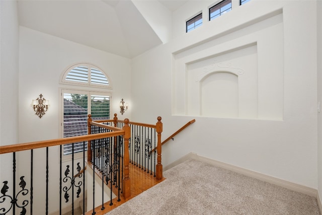 hall featuring a towering ceiling and light carpet