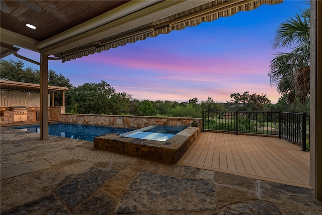 pool at dusk with a patio, a wooden deck, and an in ground hot tub