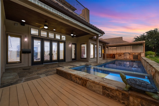 pool at dusk with ceiling fan, an in ground hot tub, and a patio area