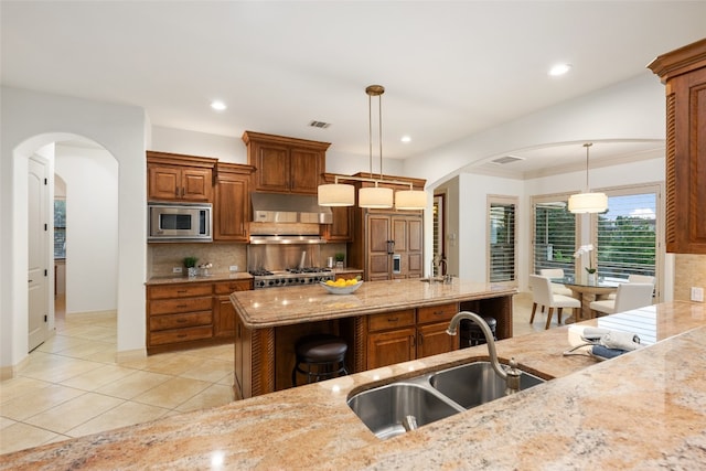 kitchen featuring backsplash, light stone countertops, pendant lighting, and appliances with stainless steel finishes