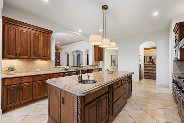 kitchen featuring decorative backsplash, decorative light fixtures, sink, and a center island with sink