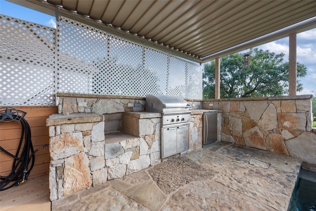 view of patio with exterior kitchen and a grill