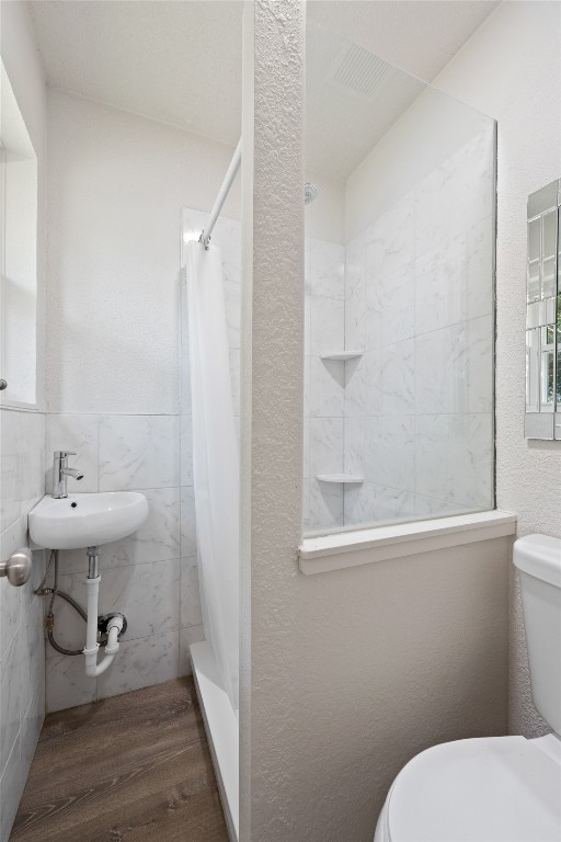 bathroom with tile walls, toilet, curtained shower, and hardwood / wood-style flooring