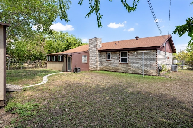 rear view of property featuring central AC and a lawn