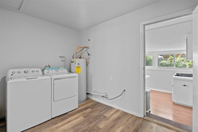 laundry room featuring water heater, washing machine and clothes dryer, and light hardwood / wood-style floors