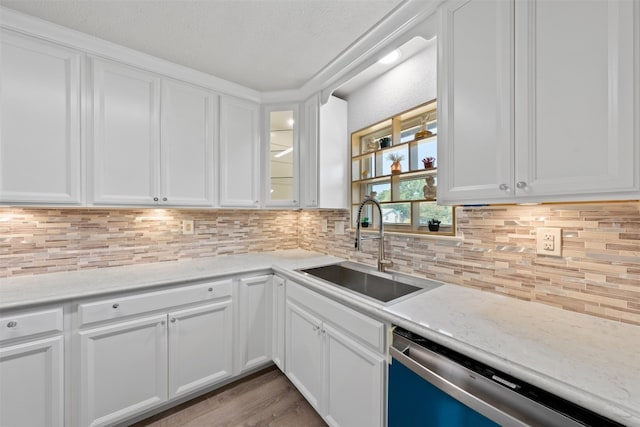 kitchen featuring light stone countertops, stainless steel dishwasher, sink, decorative backsplash, and white cabinets