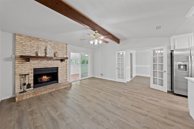 unfurnished living room with light hardwood / wood-style flooring, ceiling fan, a brick fireplace, and vaulted ceiling with beams