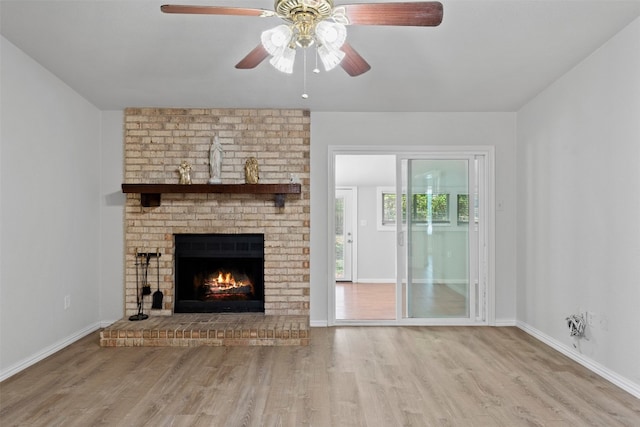 unfurnished living room with light hardwood / wood-style flooring, ceiling fan, and a brick fireplace