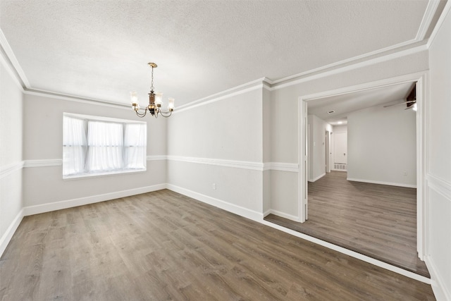 unfurnished room with crown molding, a textured ceiling, wood-type flooring, and a chandelier